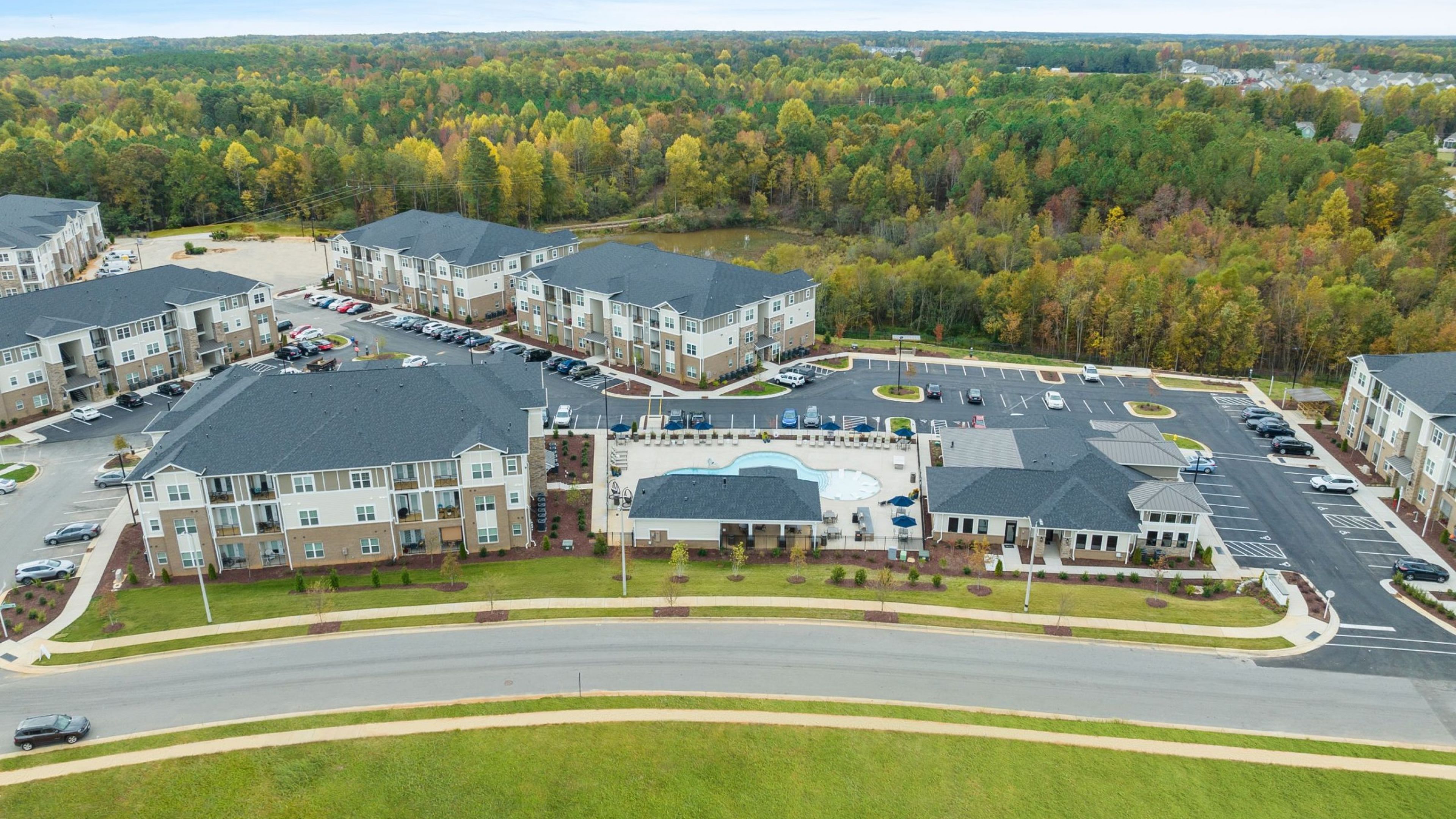 Hawthorne at Holly Springs aerial view of apartment buildings and parking, surrounded by a beautiful green forested landscape
