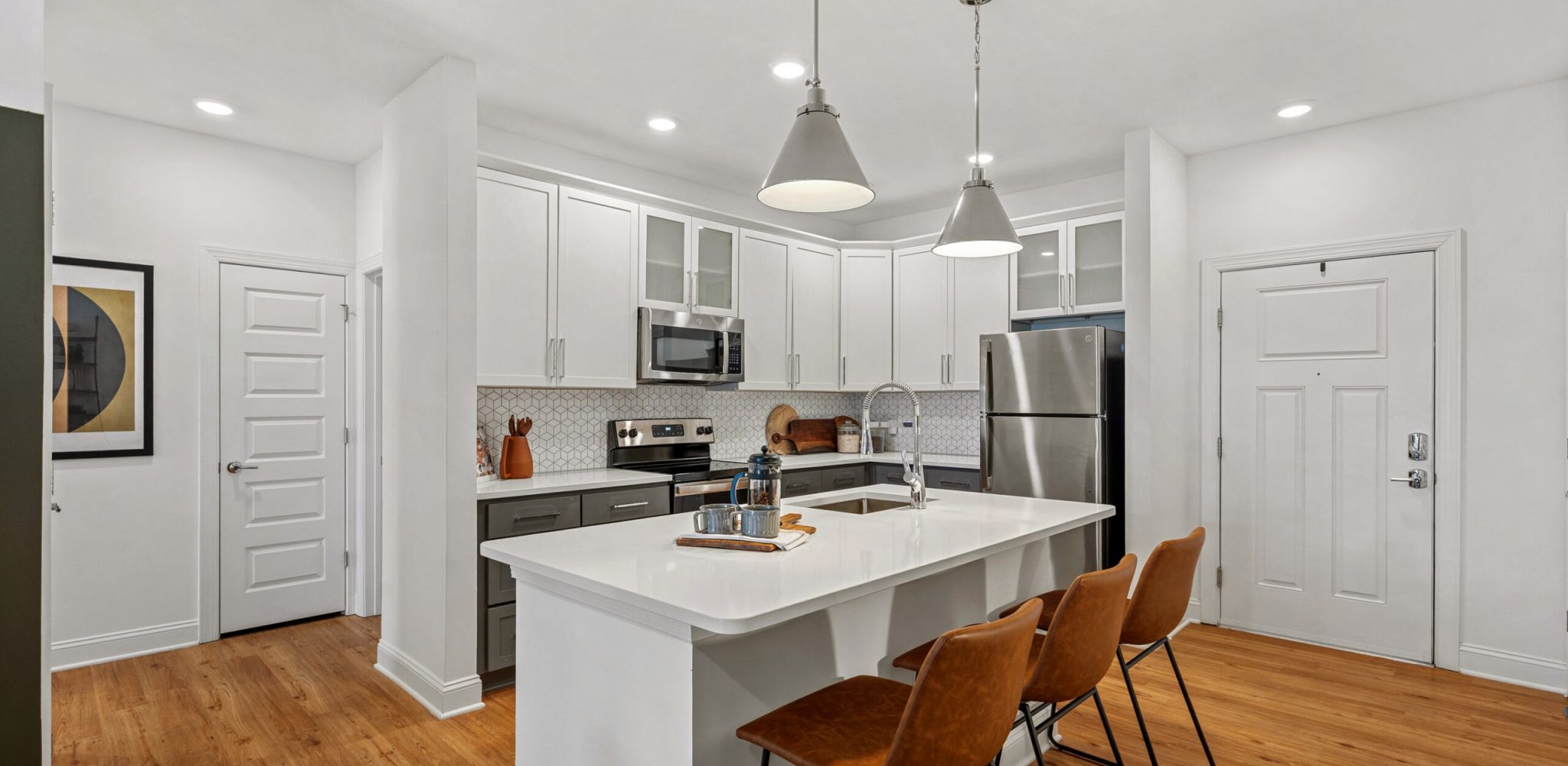 Hawthorne at Holly Springs luxury apartment kitchen with island, quartz countertops, designer tile backsplash, and stainless steel appliances